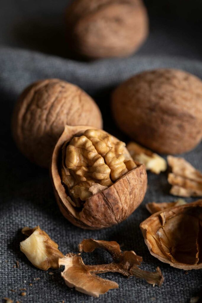 "English walnuts showing whole kernels, halved pieces, and partial shell fragments on neutral background"