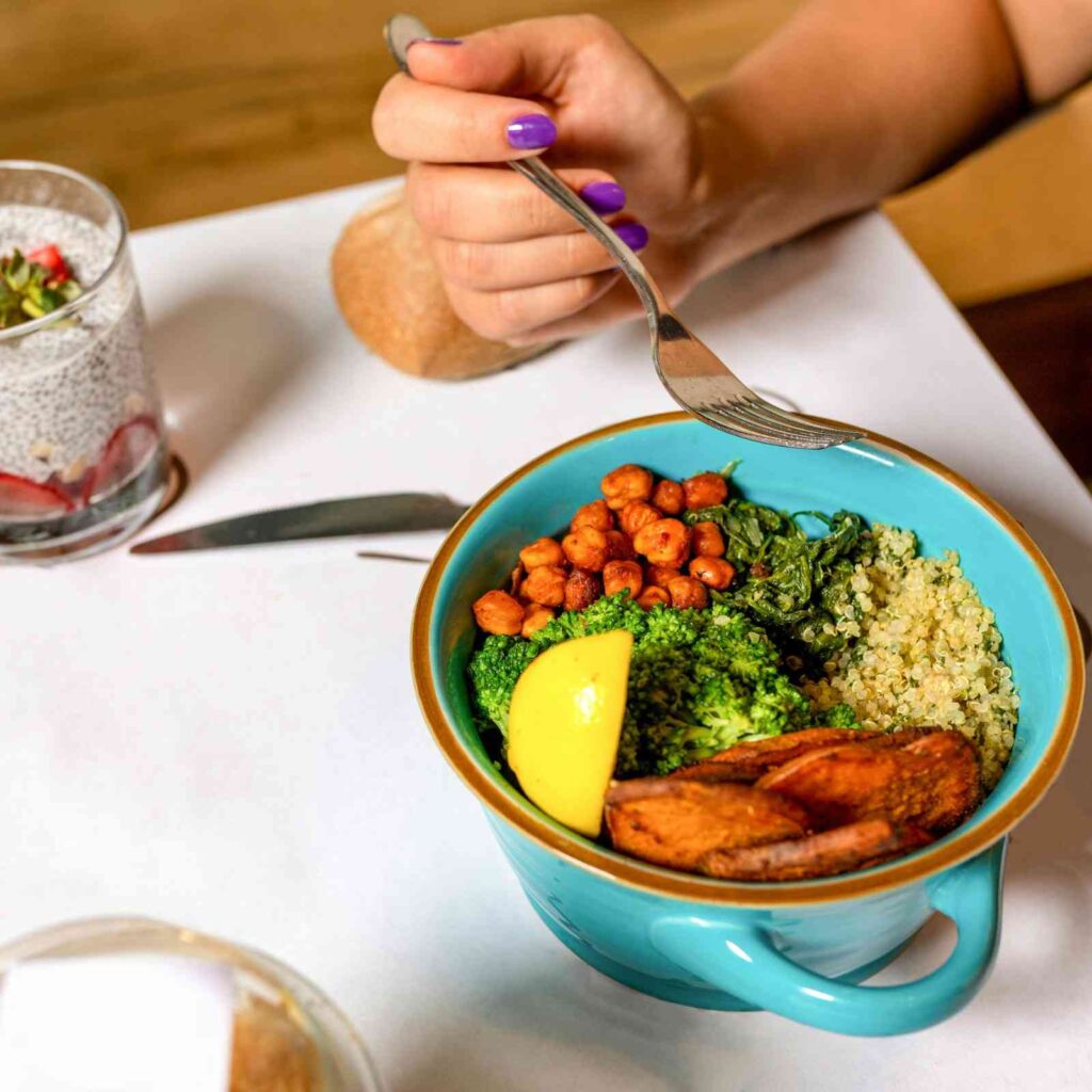 Home cook preparing a colorful bowl with lentils, quinoa, roasted vegetables, and avocado on a kitchen counter. FiberMaxxing 2026
