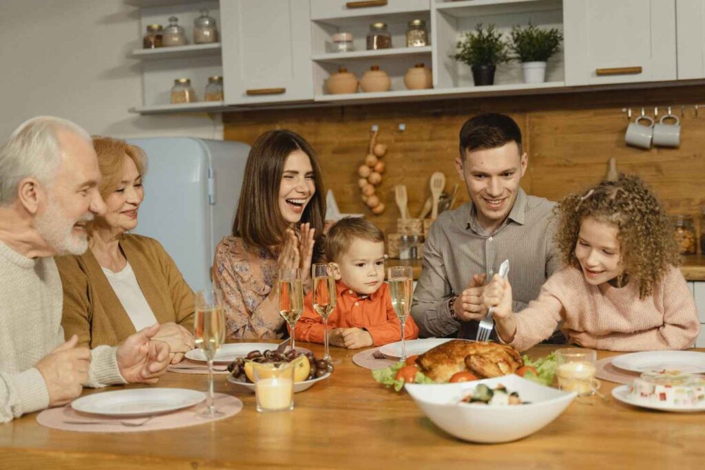 Multigenerational family sharing home-cooked meal around a rustic wooden table with conversation and laughter, representing traditional eating habits and the longevity paradox 2026
