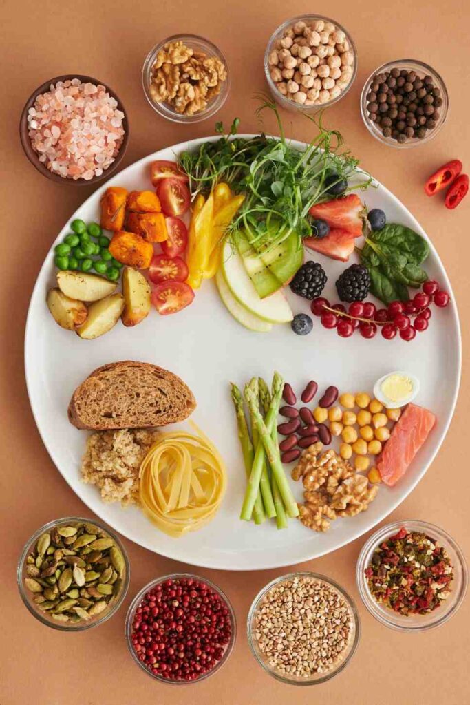 Colorful display of fiber-rich foods on wooden table including oatmeal, various beans, whole apples, almonds, and carrots